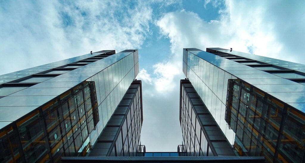 Looking up at two skyscrapers from the sidewalk